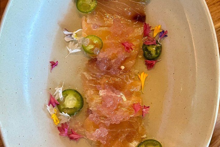 A plate of food with slices of fish and decorative flowers. 5