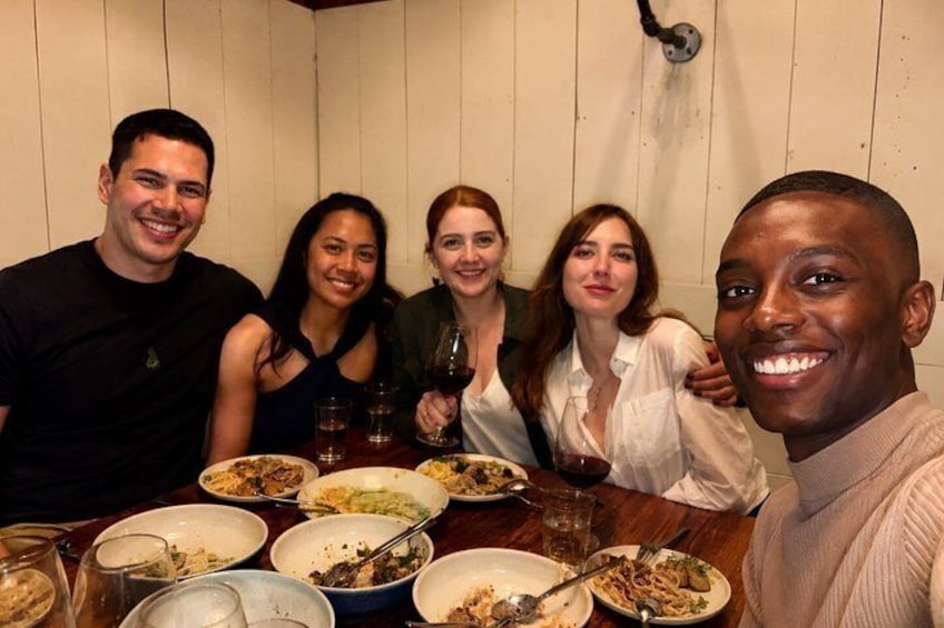 A group of people sitting around a table with plates of food and glasses of wine. 1