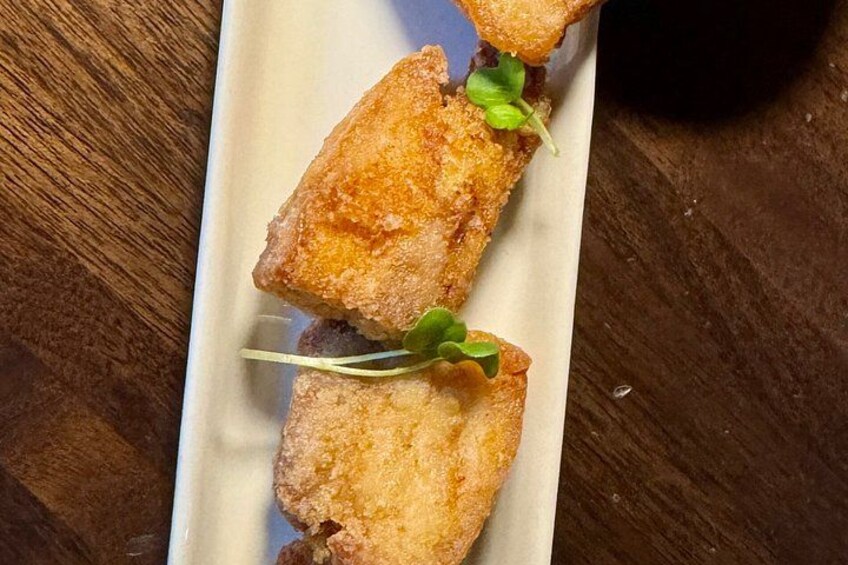 A white rectangular plate with two breaded items and a small green garnish. 3