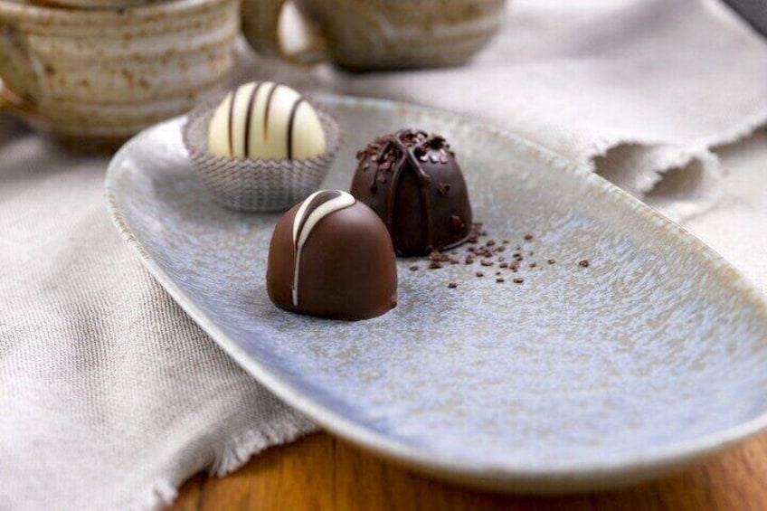 Three chocolate truffles on a ceramic plate. 3