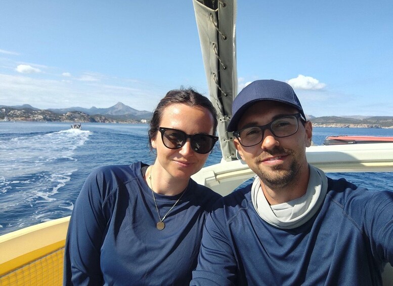 Two people on a boat with a mountainous coastline in the background. 3