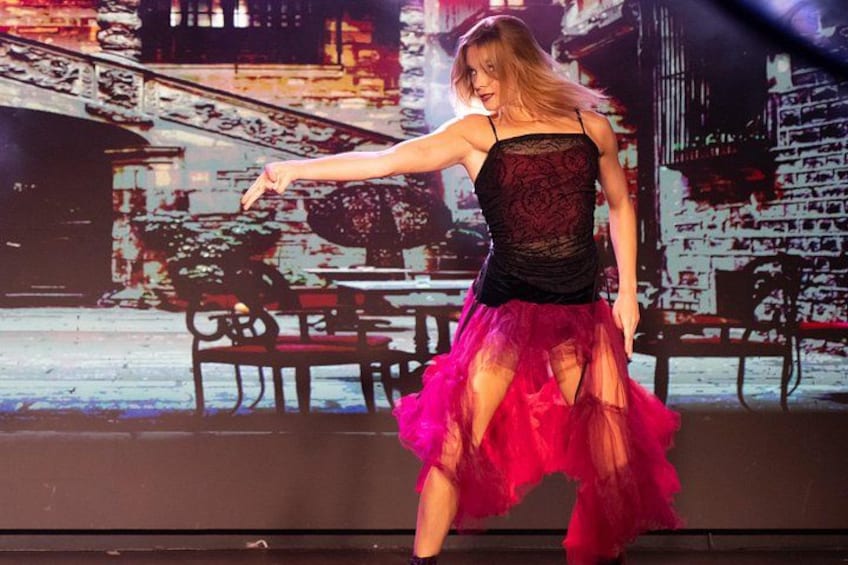 A person in a black lace top and pink skirt dancing. 4