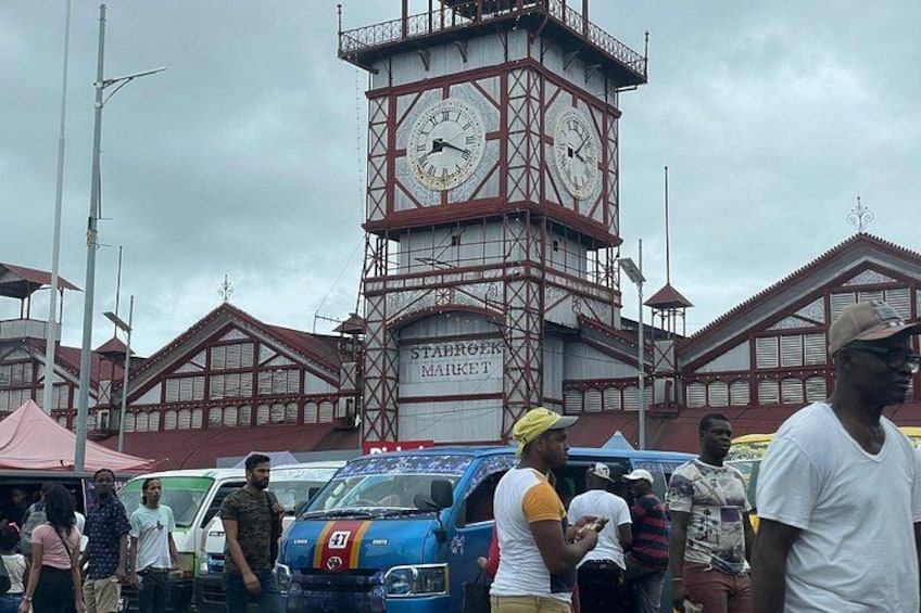 A clock tower, a market, and people. 5