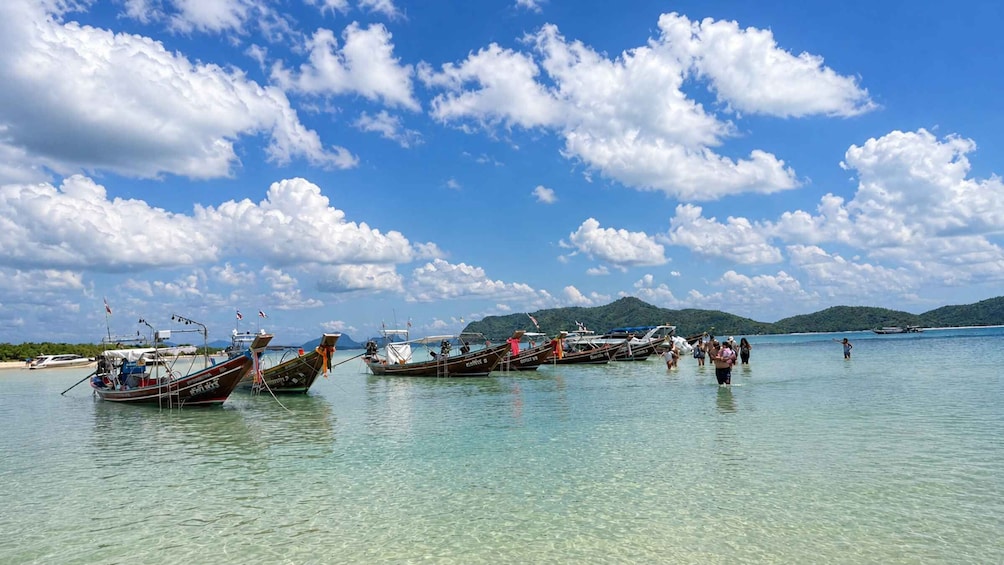 A calm coastal scene with traditional boats docked in shallow waters, clear skies, and distant green hills. 5