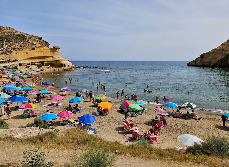 A crowded beach with colorful umbrellas and people swimming in the sea. 3