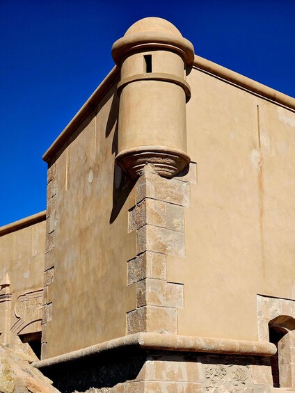 A beige building with a rounded tower and a stone base. 4