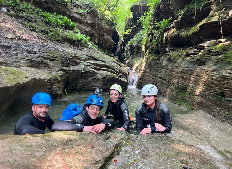 A group of people in a rocky gorge with a waterfall in the background. 1