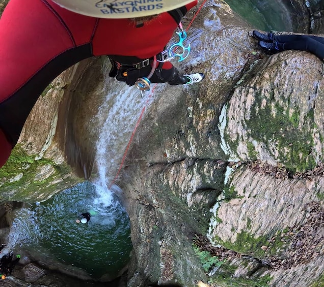 A person rappelling down a rocky cliff with a harness and ropes. 5