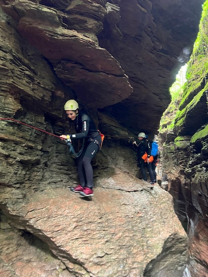 Two people rappelling in a rocky canyon with vegetation on the walls. 3
