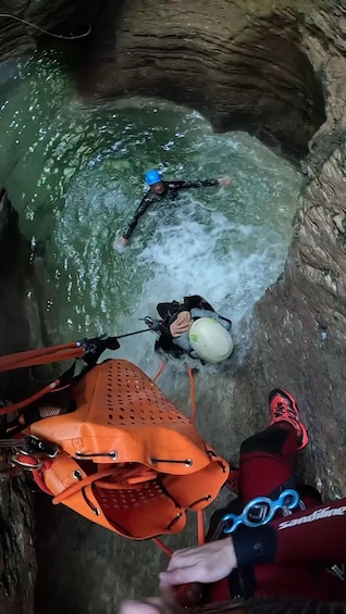 A person in a cave with water, a helmet, and a rope. 2