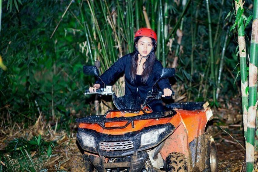 A person riding an ATV in a forested area with bamboo. 1