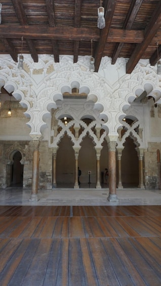An interior with wooden beams, white arches, and a tiled floor. 4