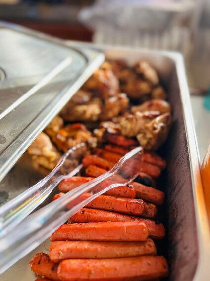 A buffet with various meats including sausages and grilled chicken. 5
