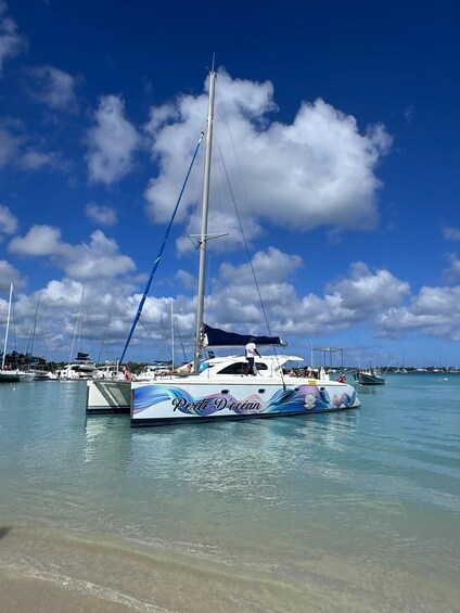 A sailboat named 'Perle D'océan' docked at a marina with other boats in the background. 1