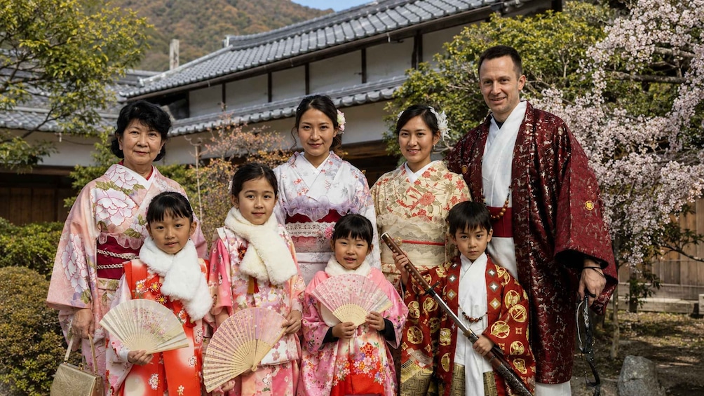 A family in traditional Japanese attire in front of a temple with cherry blossoms. 2