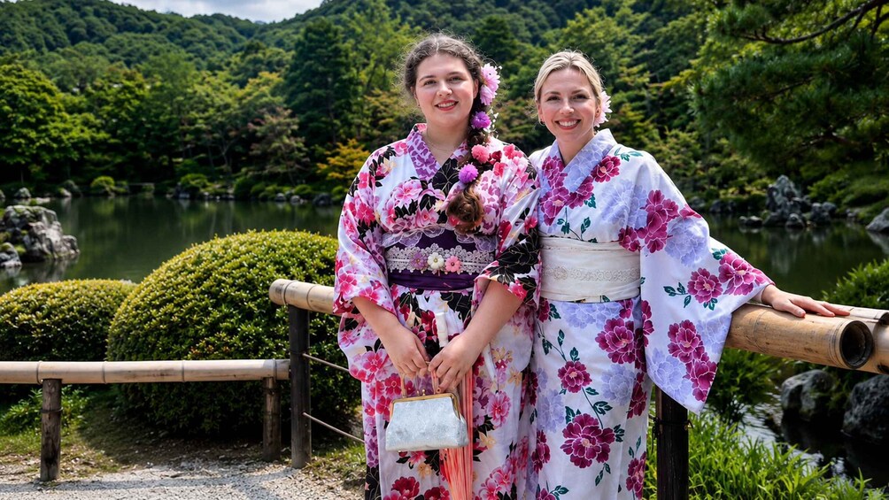 Two individuals in traditional Japanese kimonos with a mountainous landscape and a pond in the background. 5