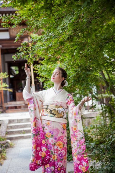 A person in traditional Japanese attire standing in a garden with a building in the background. 3