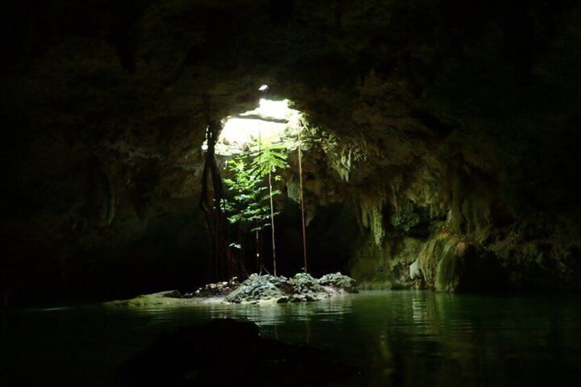 A cave with a small island illuminated by a light source, surrounded by water. 3
