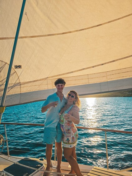 Two people on a sailboat with a clear blue sea in the background. 4