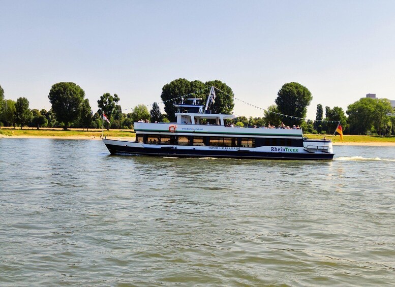 A river cruise boat with passengers, surrounded by trees and a clear sky. 5