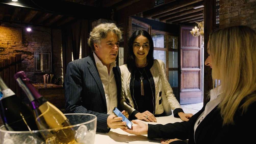 Three people at a table with a bottle and a glass. 5