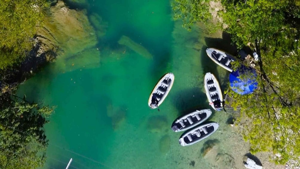 A clear turquoise lake with several boats anchored near the shore. 1