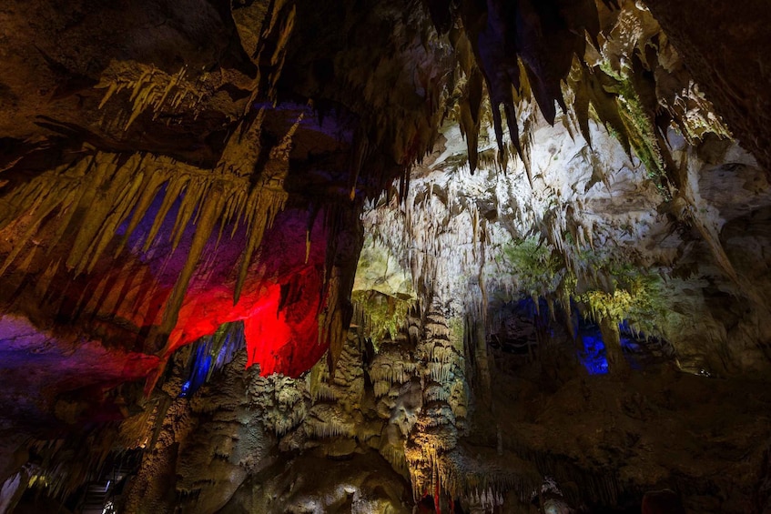 A cave with stalactites and stalagmites, illuminated by colored lights. 4