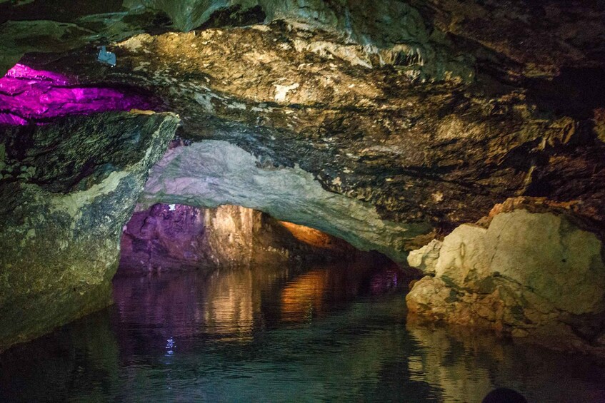 A cave with a natural archway and a pool of water reflecting the cave's interior. 2