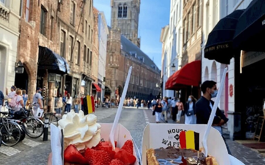 A street with buildings, a tower, and people walking. 2