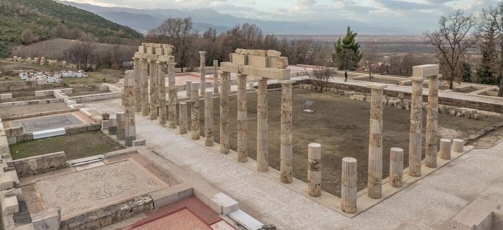 Ancient ruins with columns and a central open space, surrounded by a hilly landscape. 5