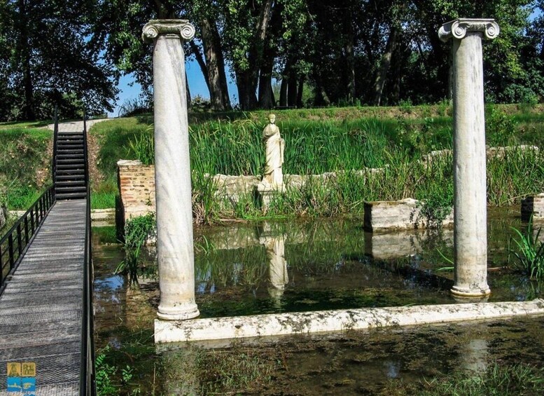A park with a statue, two columns, a bridge, and a pond. 3