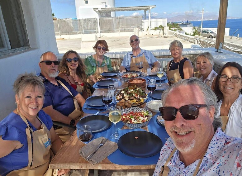 A group of people dining outdoors with a view of the sea and buildings in the background. 1