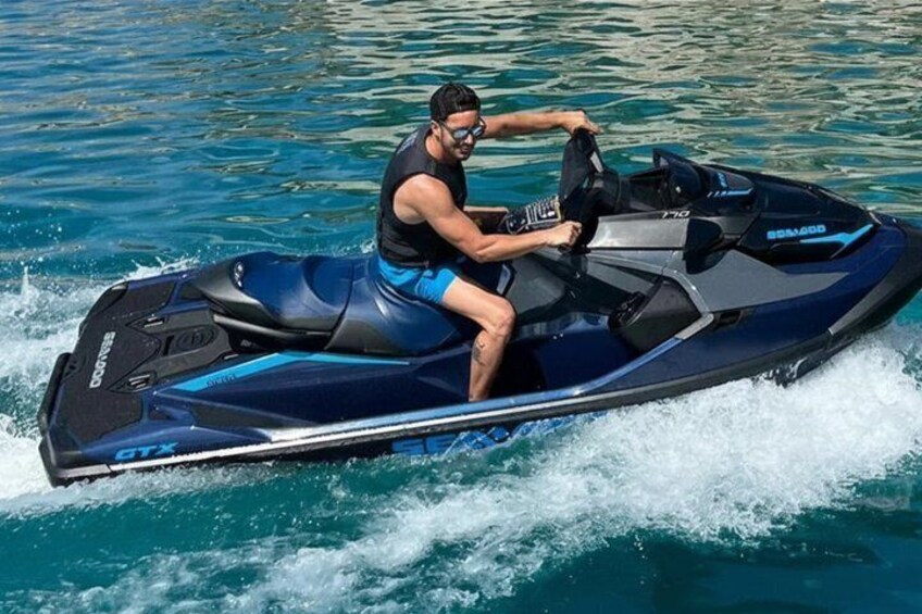 A person riding a jet ski on clear blue water. 5