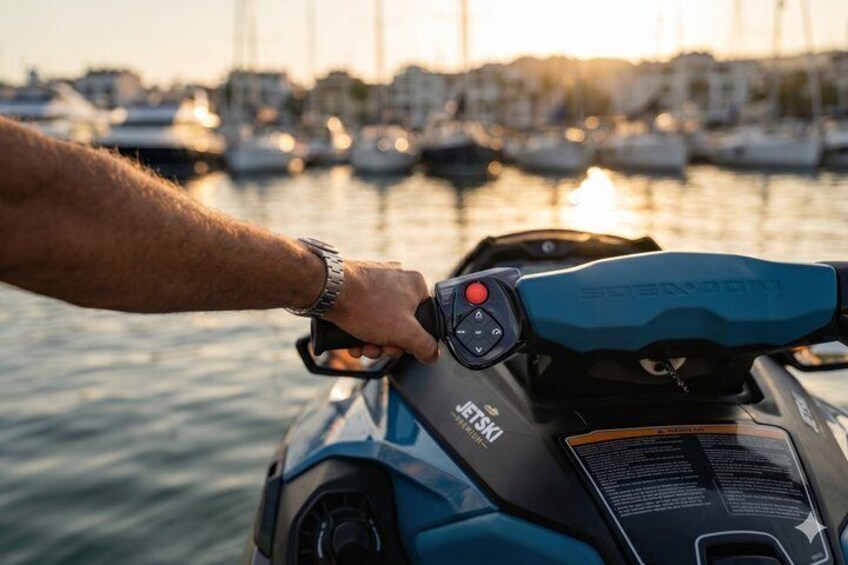 A person operating a jet ski with a marina and boats in the background. 2