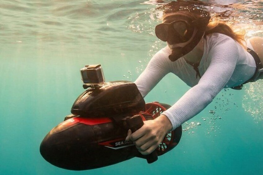 A person underwater with a scuba diving mask and a black underwater camera. 4