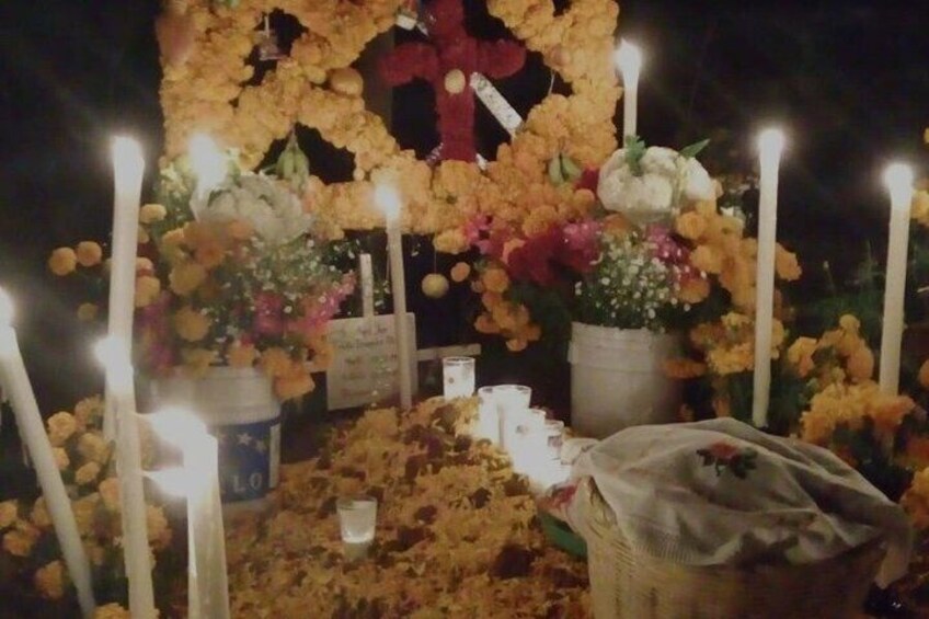 A nighttime memorial with flowers, candles, and a cross. 5