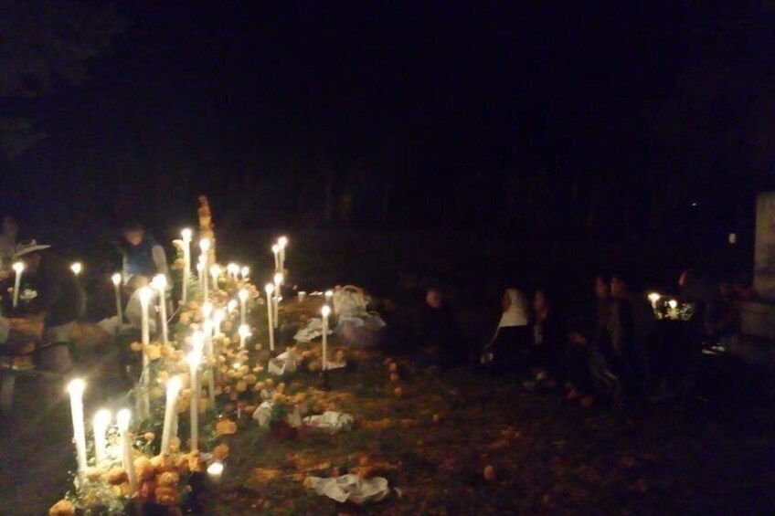 A nighttime outdoor gathering with lit candles and people. 3