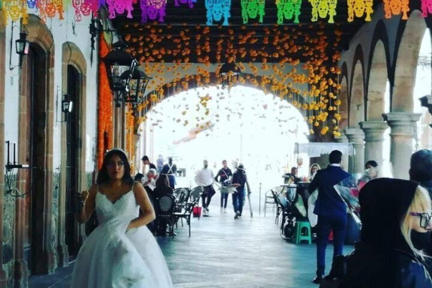 A wedding procession with a bride in a white dress, arches, and floral decorations. 1