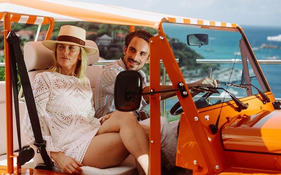 A couple in a golf cart with a scenic ocean view. 5