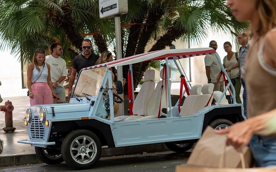 A light blue off-road vehicle with a red roof parked on a street. 4