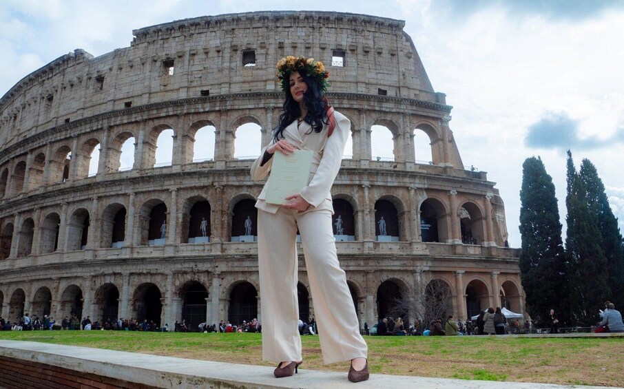 A person in front of the Colosseum with a floral headpiece, standing on a platform. 5