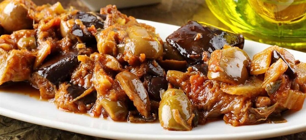 A dish of cooked eggplant with tomatoes and onions. 1
