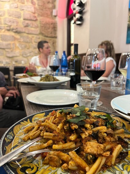 A restaurant setting with a plate of pasta and wine glasses. 5