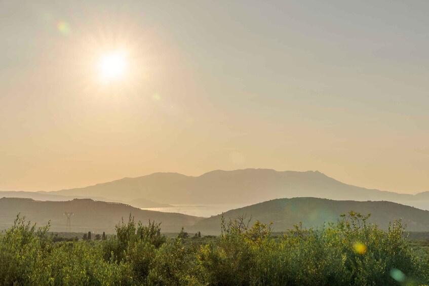 A landscape with mountains, a body of water, and a power line tower. 5