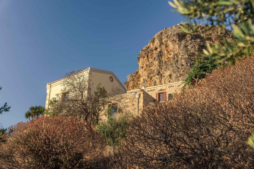 A building with a stone facade, a large rock formation, and sparse vegetation. 3