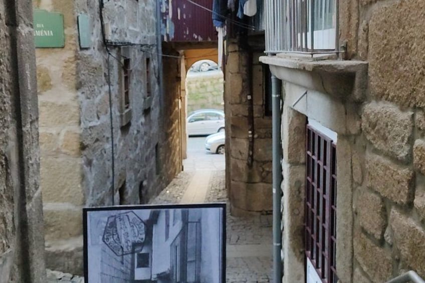 A narrow alleyway with stone walls, a metal gate, and a parked car. 3