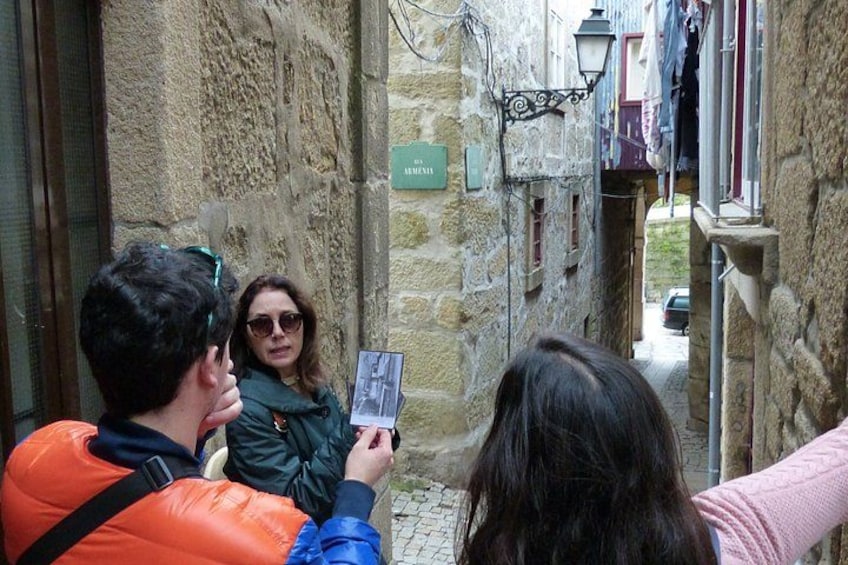 A narrow alley with stone walls, a street lamp, and a sign. 4