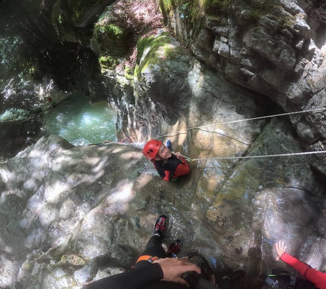 A person rappelling down a rocky cliff with a rope. 5