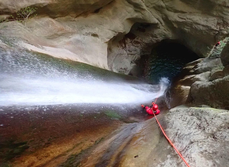 A person rappelling down a waterfall in a cave. 1