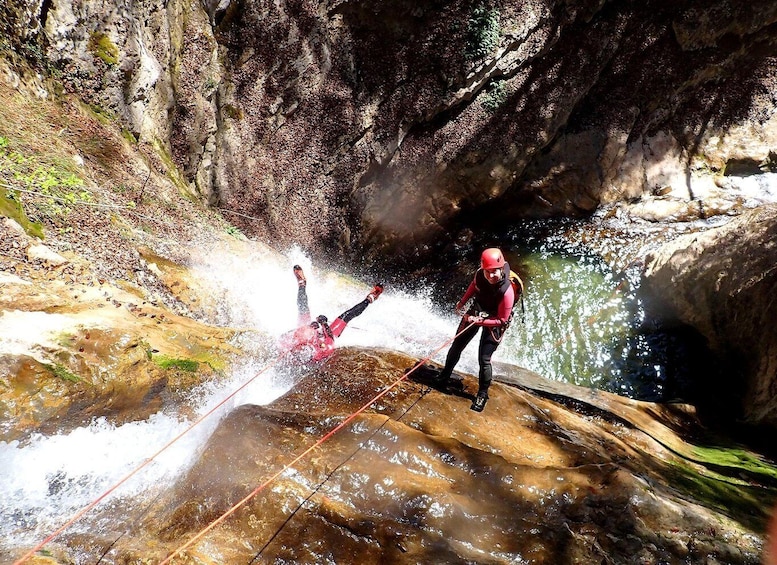 A person rappelling down a rocky cliff into a body of water. 3
